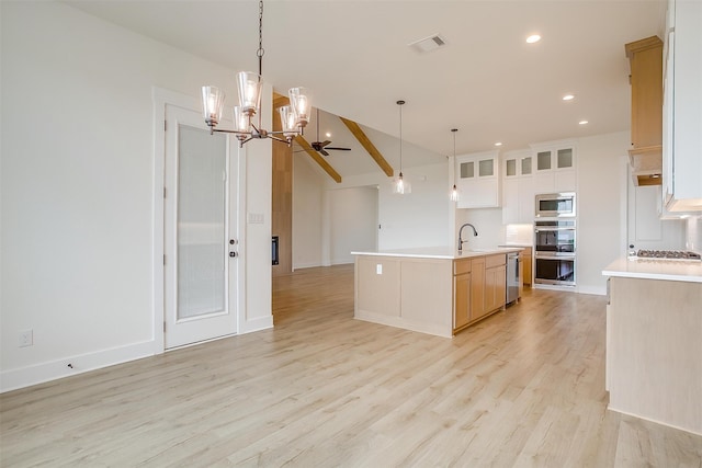 kitchen with light wood-type flooring, a kitchen island with sink, ceiling fan with notable chandelier, decorative light fixtures, and lofted ceiling with beams