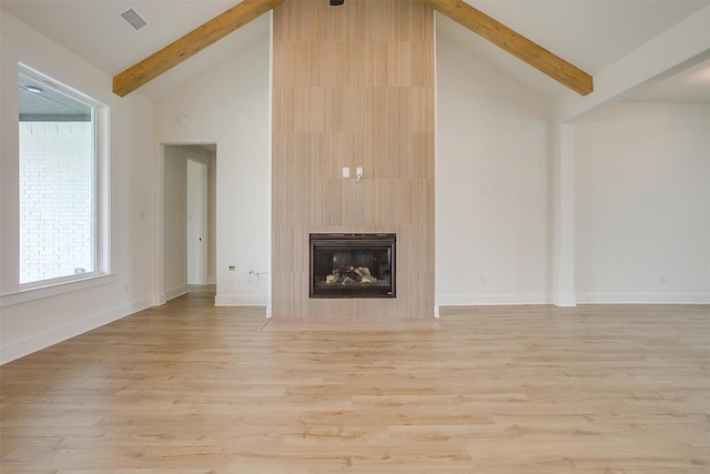 unfurnished living room with high vaulted ceiling, a fireplace, light hardwood / wood-style floors, and beamed ceiling