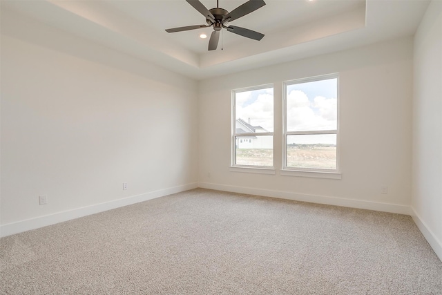 unfurnished room featuring carpet, ceiling fan, and a tray ceiling