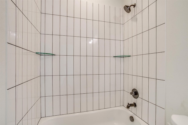 bathroom with tiled shower / bath combo and toilet