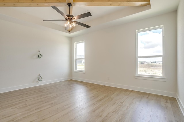 spare room with a raised ceiling, ceiling fan, and light hardwood / wood-style floors