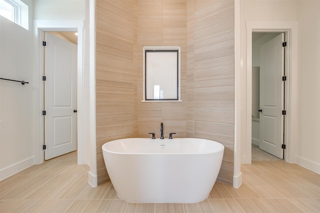 bathroom with a tub to relax in, tile walls, and tile patterned floors