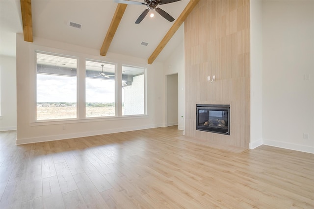 unfurnished living room with a tiled fireplace, light wood-type flooring, high vaulted ceiling, beamed ceiling, and ceiling fan