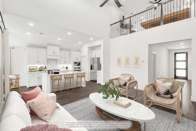 living room featuring high vaulted ceiling, dark wood-type flooring, sink, and ceiling fan