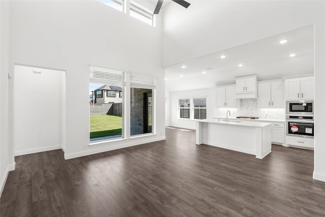 unfurnished living room with sink, dark wood-type flooring, a high ceiling, and ceiling fan