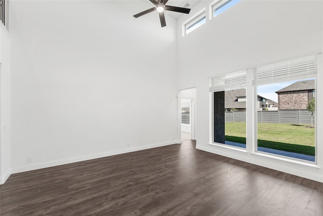 unfurnished living room featuring ceiling fan, a high ceiling, and dark hardwood / wood-style flooring