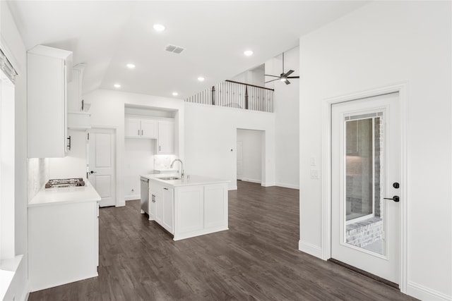 kitchen with white cabinets, a center island with sink, dark hardwood / wood-style flooring, a towering ceiling, and sink