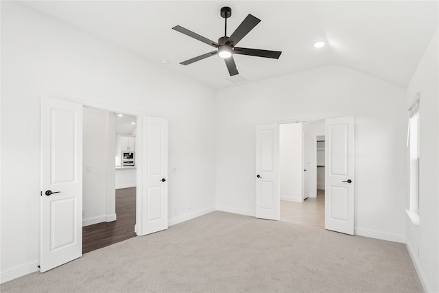 unfurnished bedroom featuring light carpet, vaulted ceiling, and ceiling fan