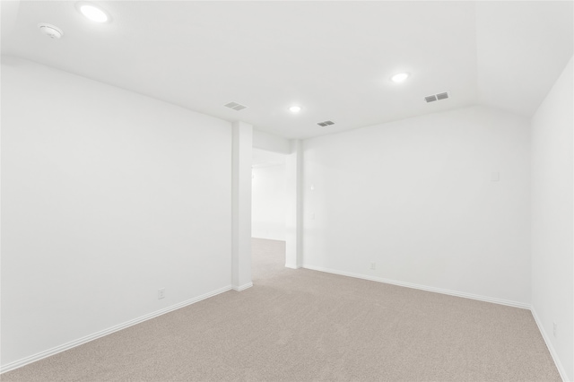 empty room featuring light carpet and vaulted ceiling