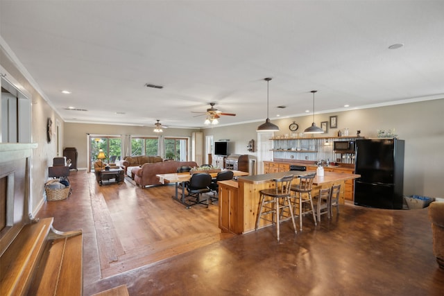 kitchen featuring black appliances, ceiling fan, crown molding, and a breakfast bar area