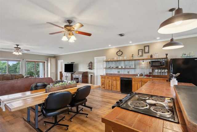 kitchen featuring sink, light hardwood / wood-style flooring, crown molding, pendant lighting, and black appliances