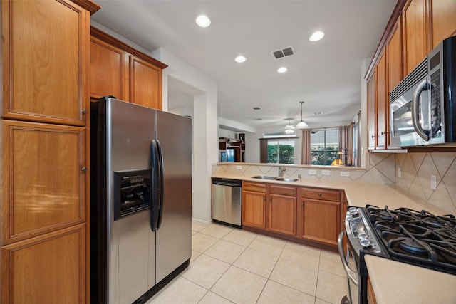 kitchen with kitchen peninsula, decorative backsplash, stainless steel appliances, ceiling fan, and sink