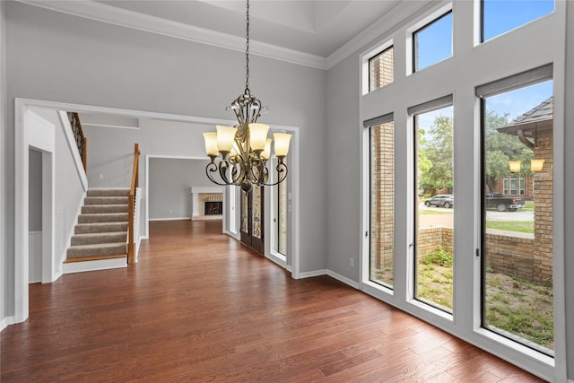 foyer entrance with dark hardwood / wood-style flooring, ornamental molding, and a chandelier