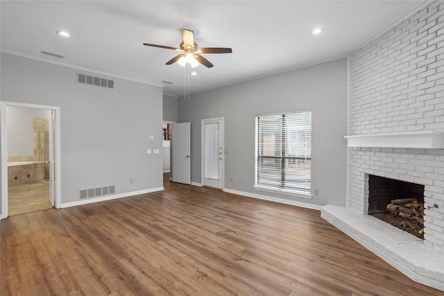 unfurnished living room with a brick fireplace, hardwood / wood-style flooring, crown molding, and ceiling fan