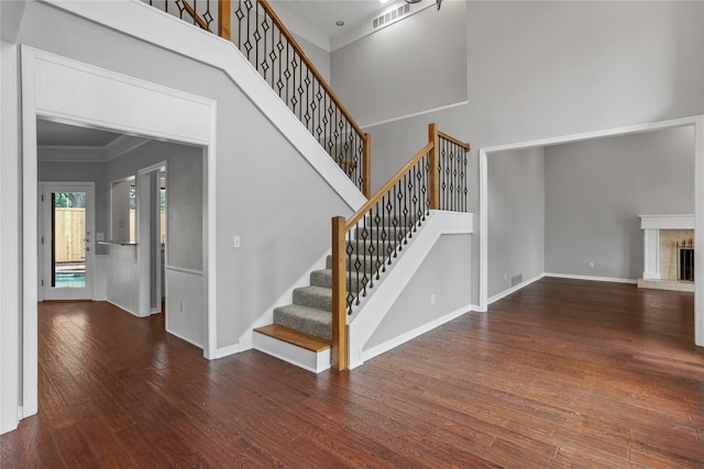 stairs featuring hardwood / wood-style flooring, a high ceiling, and crown molding