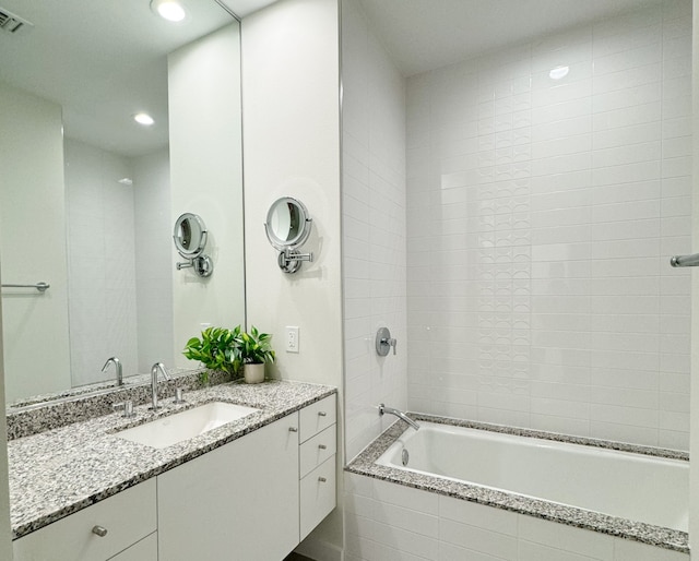 bathroom with vanity with extensive cabinet space and tiled shower / bath combo