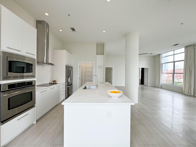 kitchen with stainless steel appliances, sink, white cabinetry, and light tile floors