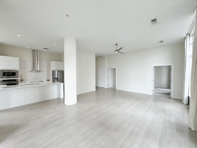 unfurnished living room featuring sink, light tile flooring, and ceiling fan