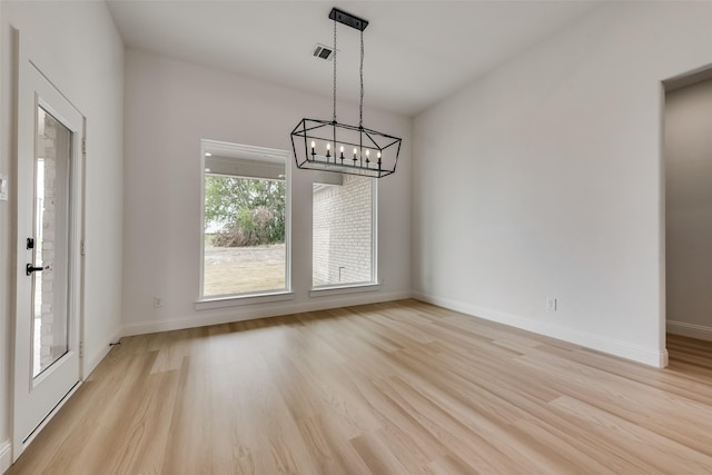 unfurnished dining area with light hardwood / wood-style floors and an inviting chandelier