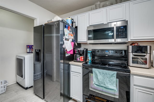 kitchen featuring light tile flooring, white cabinets, black range with electric stovetop, and washer / dryer