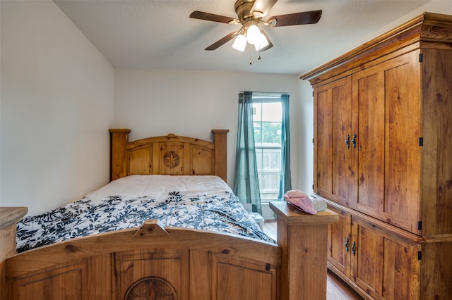 bedroom with a textured ceiling, wood-type flooring, and ceiling fan