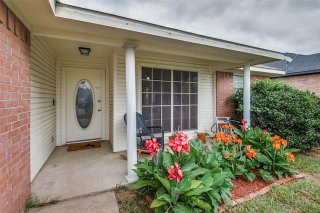 entrance to property featuring covered porch and brick siding