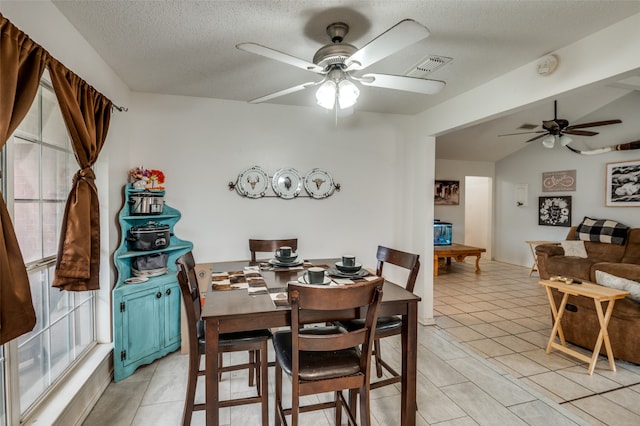 dining room with a textured ceiling, ceiling fan, light tile floors, and lofted ceiling