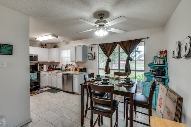 tiled dining space with sink, a textured ceiling, and ceiling fan