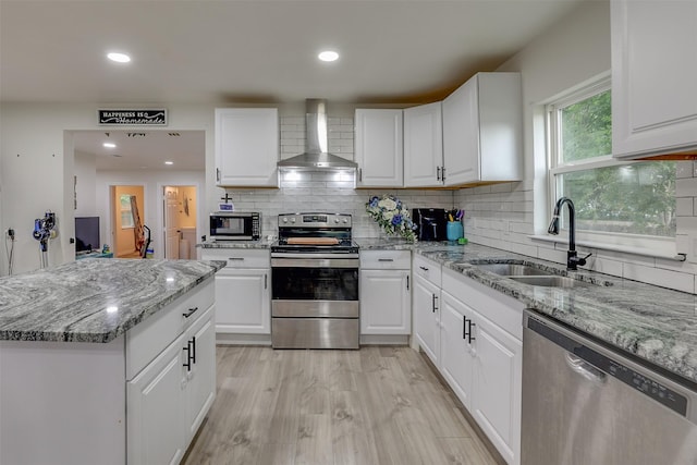 kitchen featuring appliances with stainless steel finishes, white cabinetry, and wall chimney exhaust hood