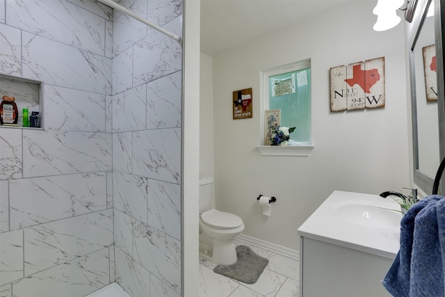 bathroom with a tile shower, vanity, and toilet