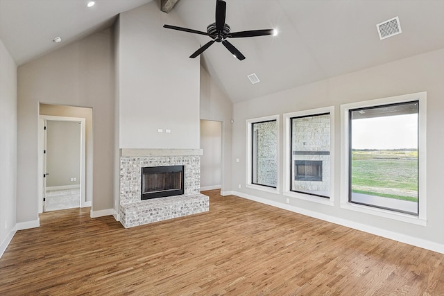 unfurnished living room with hardwood / wood-style flooring, beamed ceiling, a fireplace, high vaulted ceiling, and ceiling fan