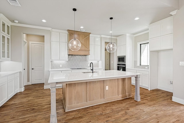 kitchen featuring wood-type flooring, sink, a center island with sink, and white cabinets