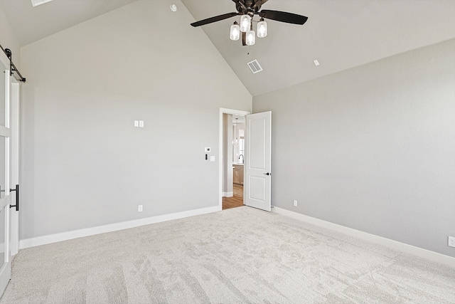 carpeted empty room featuring a barn door, high vaulted ceiling, and ceiling fan