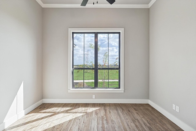 empty room featuring ceiling fan, hardwood / wood-style flooring, a wealth of natural light, and crown molding