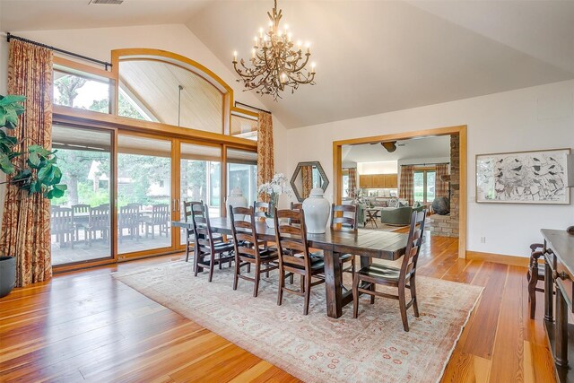 dining space with a chandelier, high vaulted ceiling, and wood-type flooring