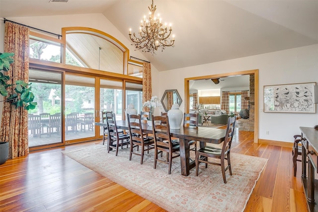 dining area featuring an inviting chandelier, high vaulted ceiling, and light wood-type flooring