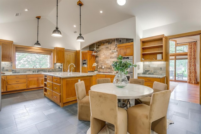 kitchen with sink, tasteful backsplash, a center island with sink, pendant lighting, and stainless steel appliances