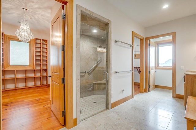 bathroom featuring vanity, wood-type flooring, a notable chandelier, and a shower with shower door