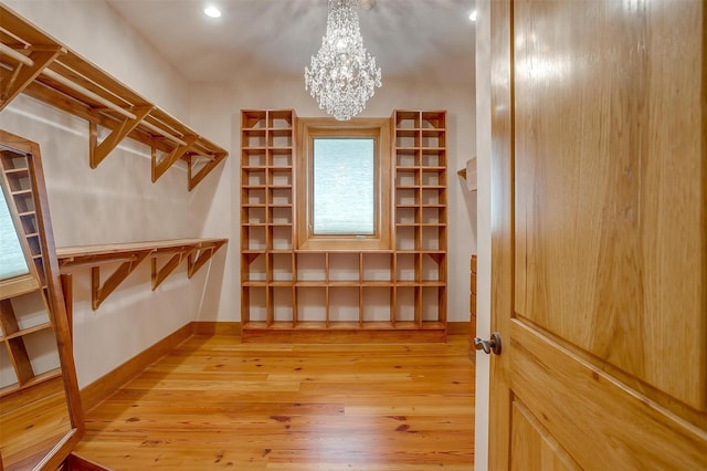 spacious closet featuring a notable chandelier and light wood-type flooring