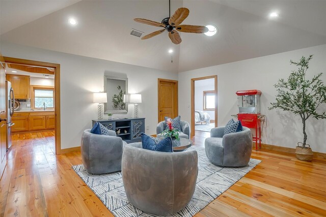 living room with ceiling fan, light hardwood / wood-style floors, and lofted ceiling