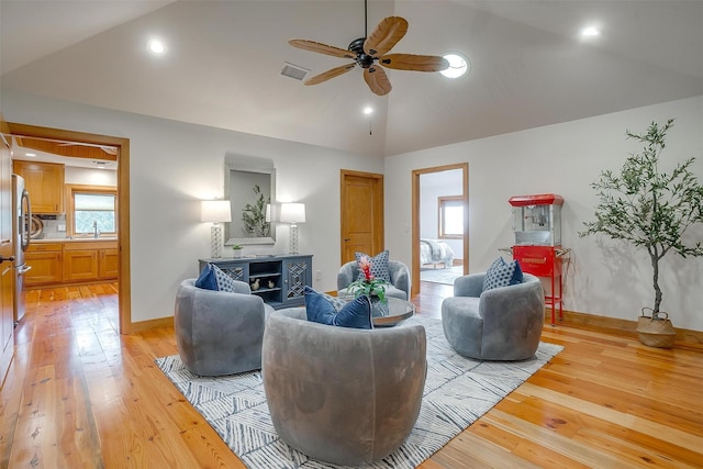 living room featuring lofted ceiling, sink, ceiling fan, and light wood-type flooring