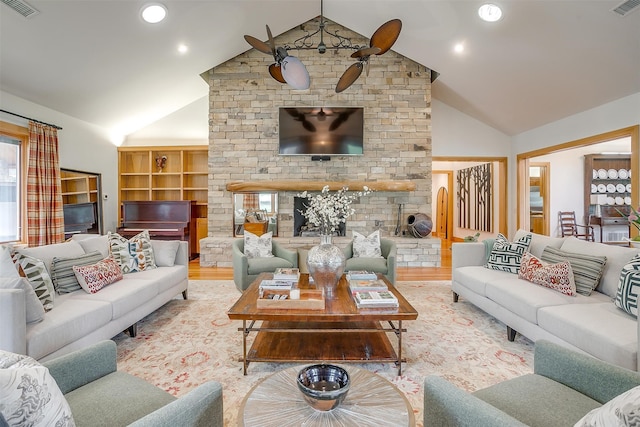 living room with hardwood / wood-style flooring, built in shelves, a large fireplace, high vaulted ceiling, and ceiling fan