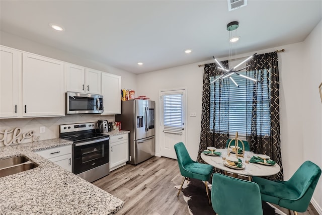 kitchen with stainless steel appliances, light hardwood / wood-style flooring, white cabinets, and tasteful backsplash