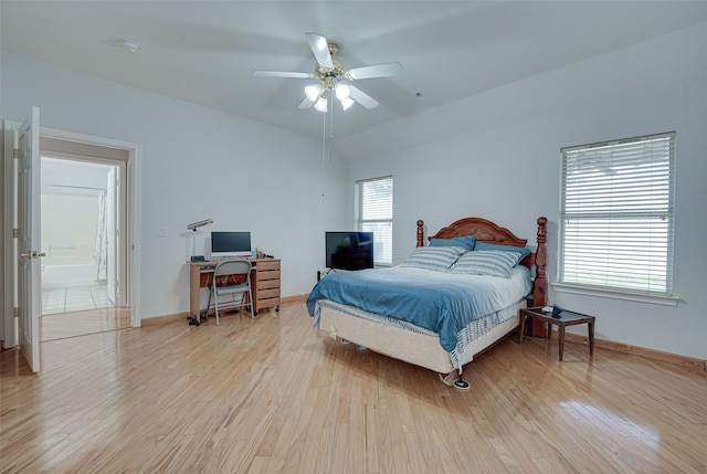 bedroom with ceiling fan, light hardwood / wood-style flooring, ensuite bath, and vaulted ceiling