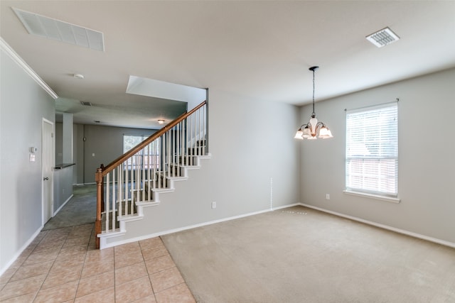 carpeted spare room featuring ornamental molding and a notable chandelier