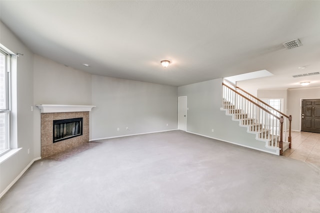 unfurnished living room featuring light carpet and a tile fireplace