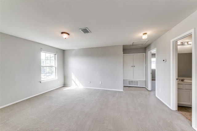 carpeted empty room with a sink, visible vents, and baseboards