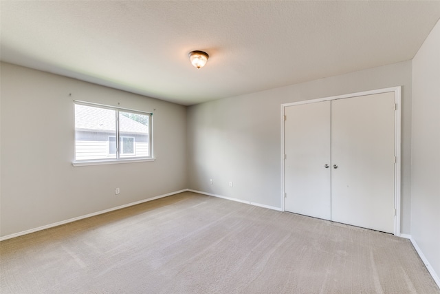 unfurnished bedroom with light carpet, a textured ceiling, and a closet