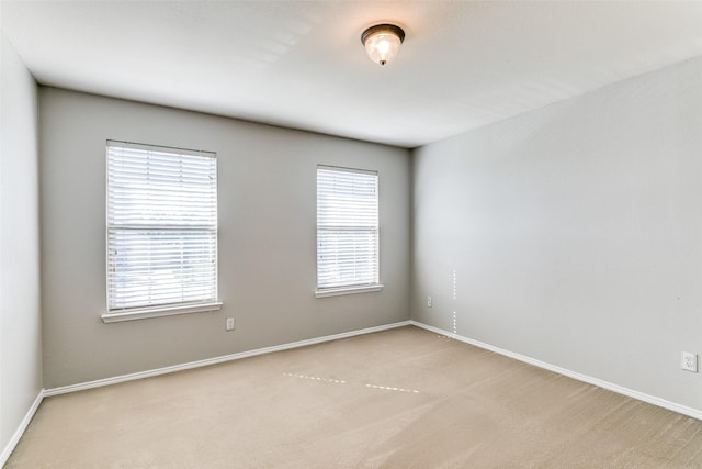 spare room with carpet floors, baseboards, and a healthy amount of sunlight