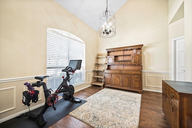 exercise room featuring dark wood-type flooring, a chandelier, and vaulted ceiling